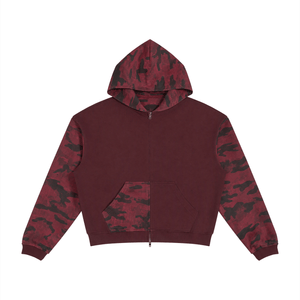A cropped zip-up hoodie with a solid burgundy body and sleeves featuring a dark red and black camouflage pattern, shown flat on a white background.