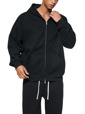 Person wearing a black zip-up hoodie and pants on a white background