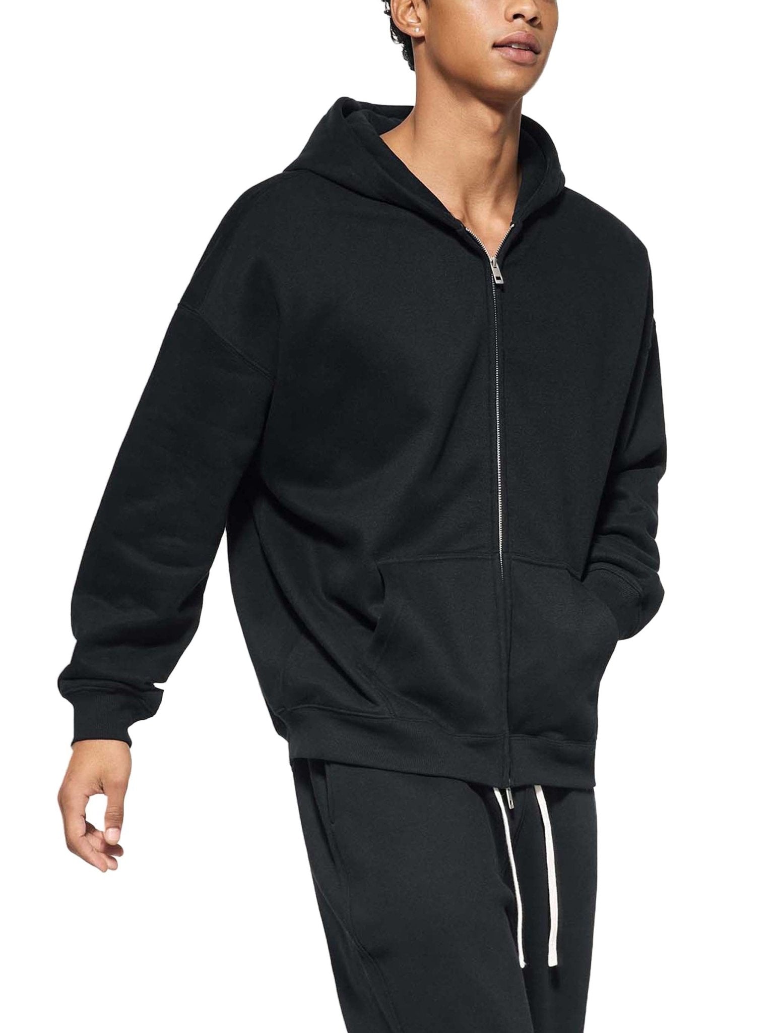 Person wearing a black zip-up hoodie and pants on a white background
