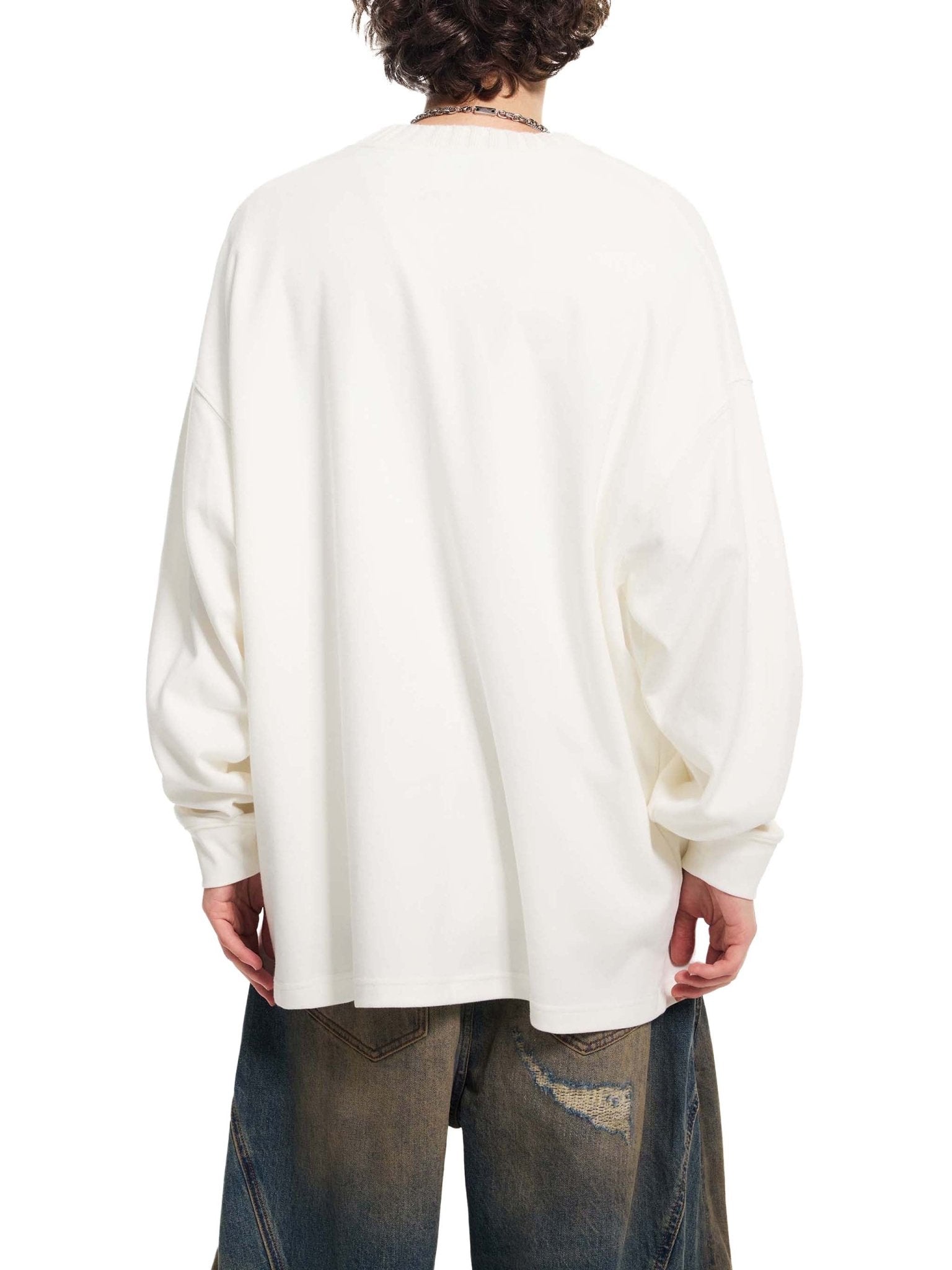 Person wearing a white oversized sweater and jeans on a white background