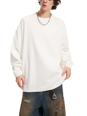Person wearing a white oversized sweatshirt and dark jeans on a white background