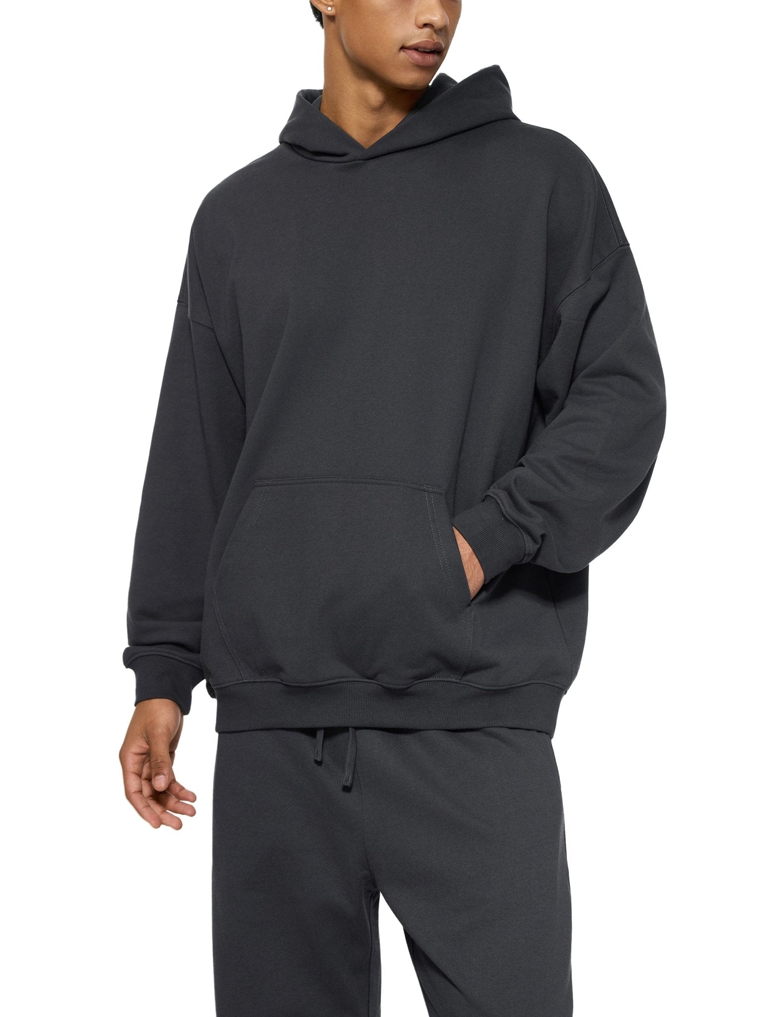 Person wearing a black hoodie and pants on a white background