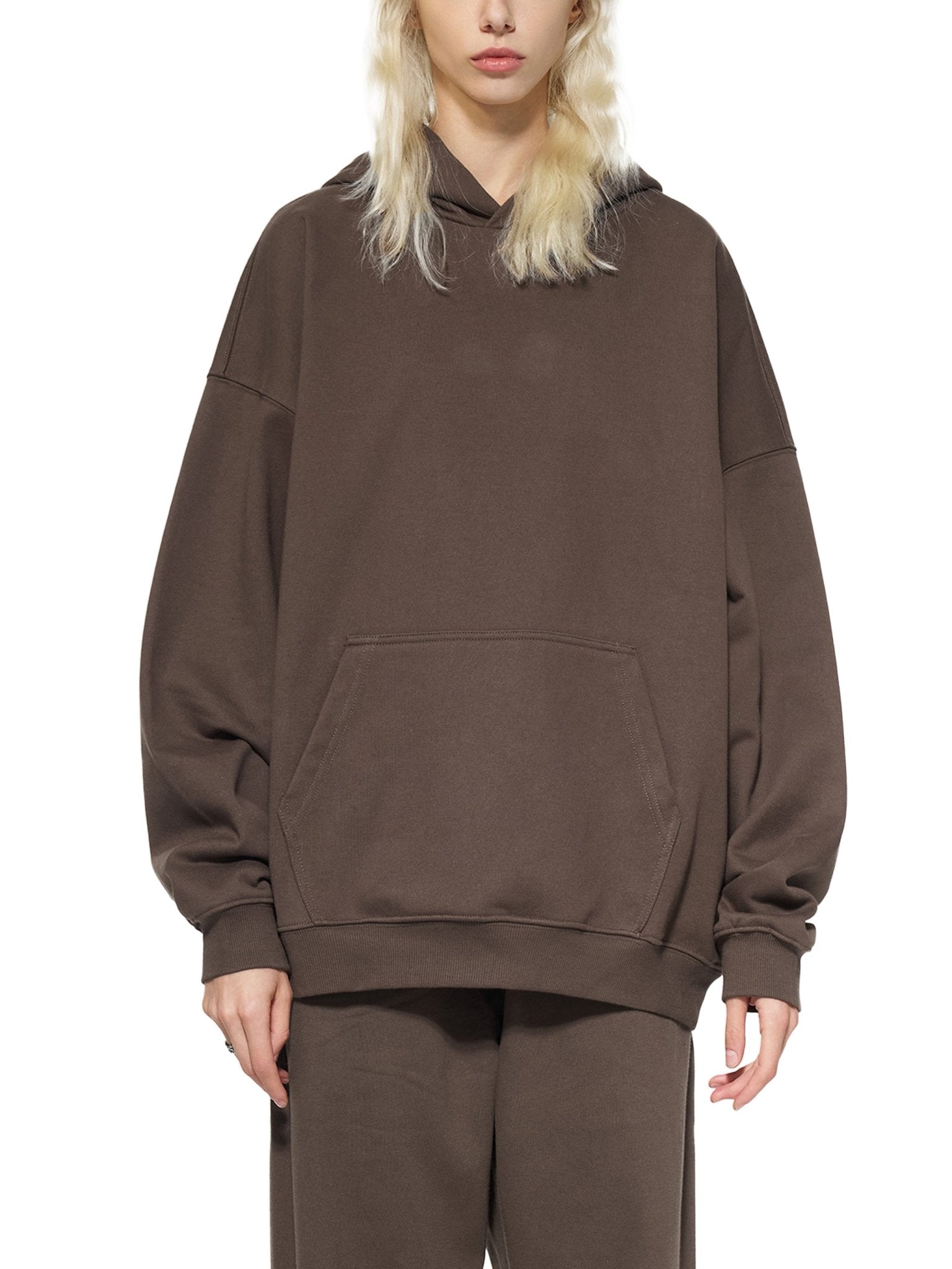 Person wearing a brown hoodie and pants on a white background