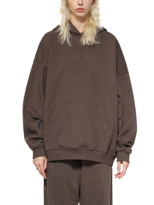 Person wearing a brown hoodie and pants on a white background