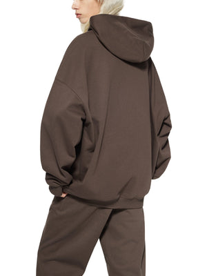Person wearing a brown hoodie and pants on a white background