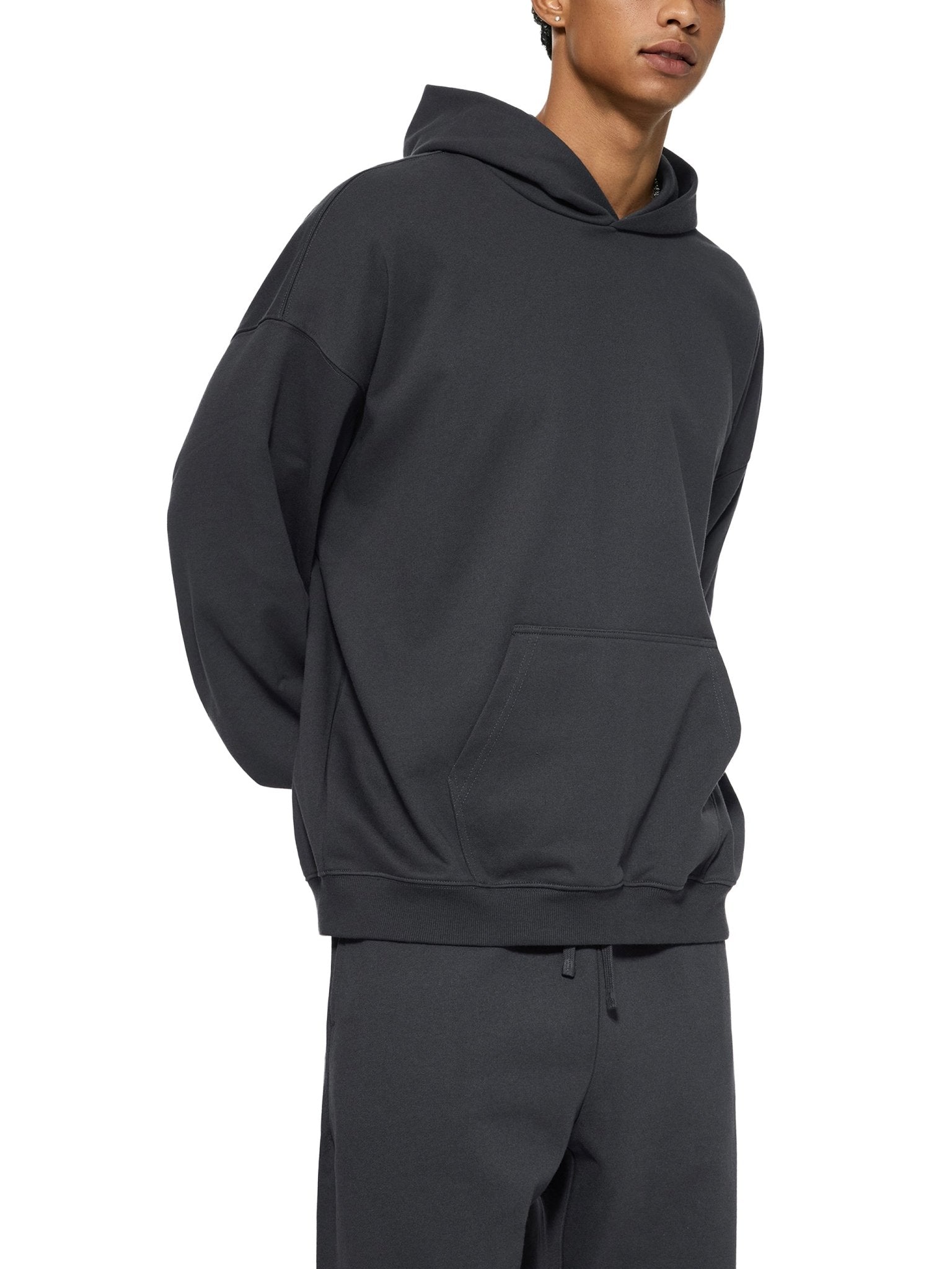 Person wearing a black hoodie and pants on a white background