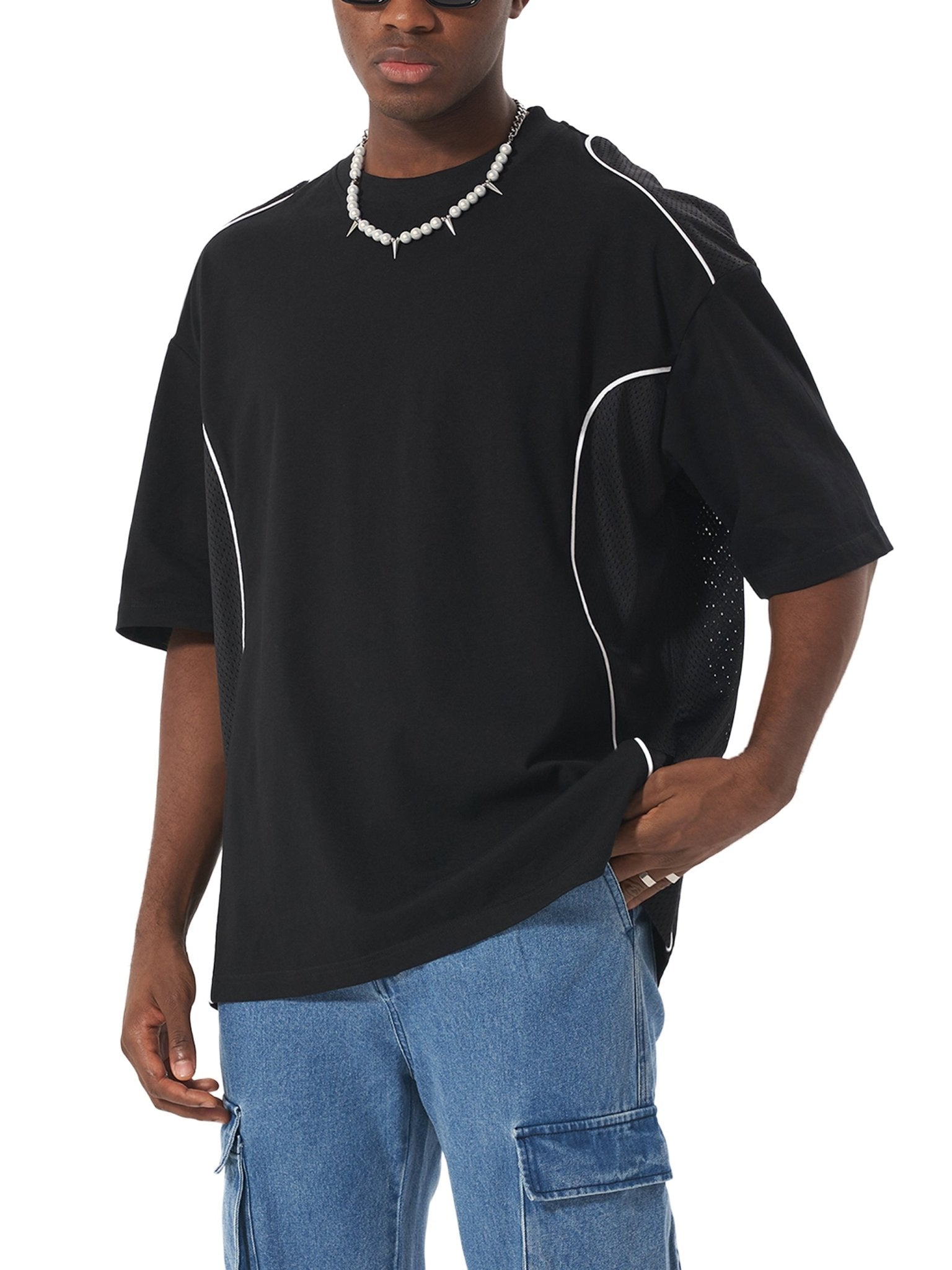 Person wearing a black t-shirt with white accents and blue jeans on a white background