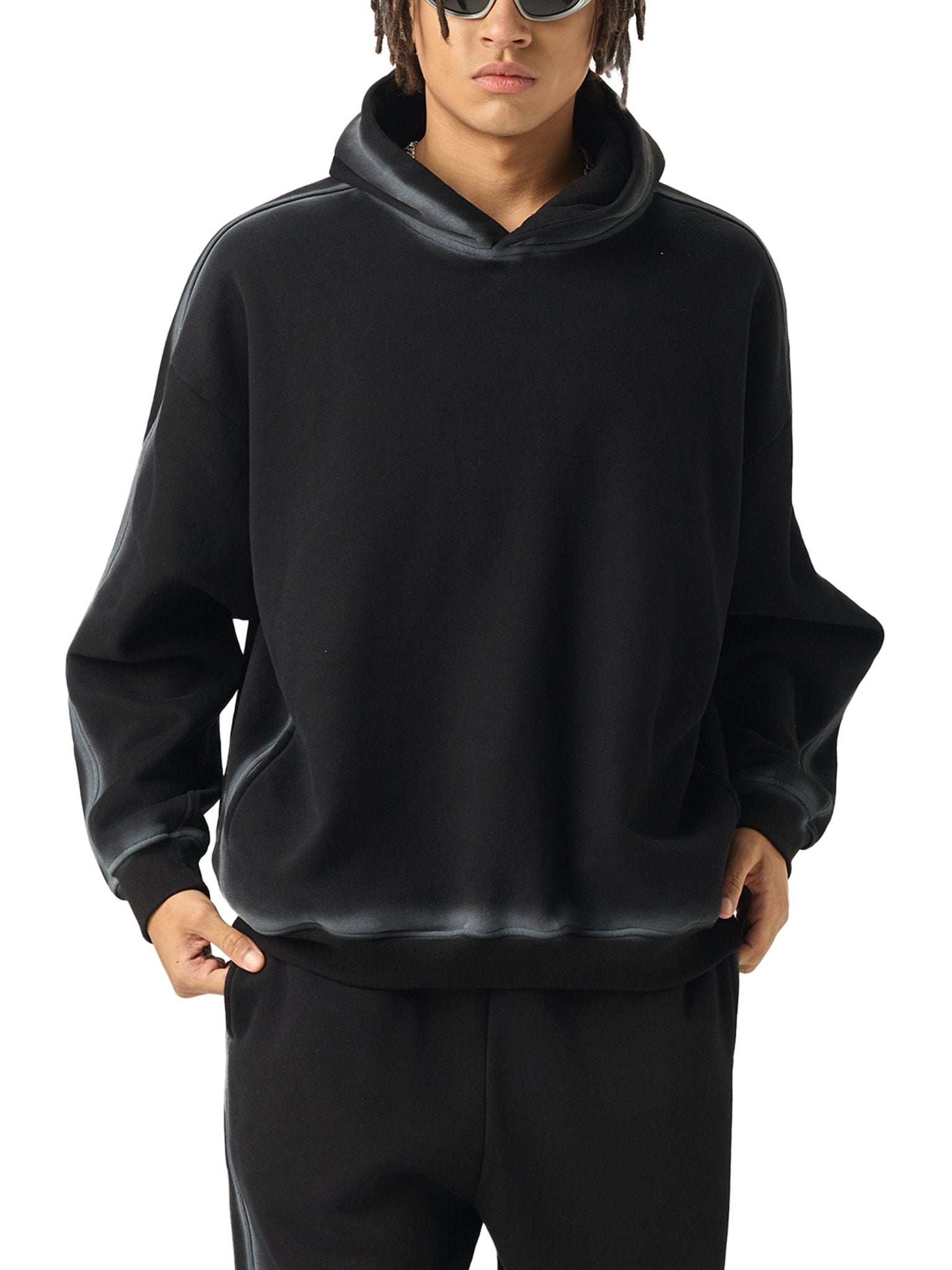 Person wearing a black hoodie and pants on a white background