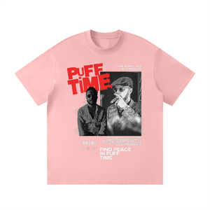 A light pink short-sleeve t-shirt with a graphic print on the front. The graphic features the text 'PUFF TIME' in bold red letters, a black-and-white photo of a man smoking a cigar, and additional white text reading 'FIND PEACE IN PUFF TIME'.