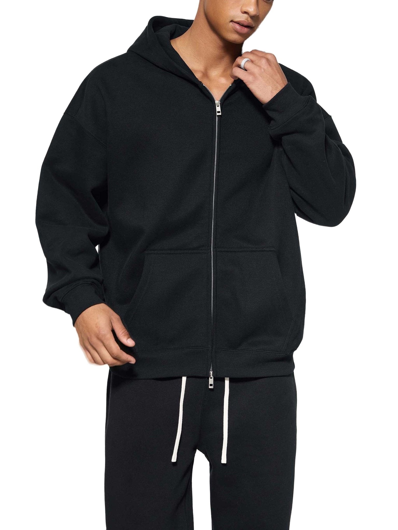 Person wearing a black zip-up hoodie and pants on a white background