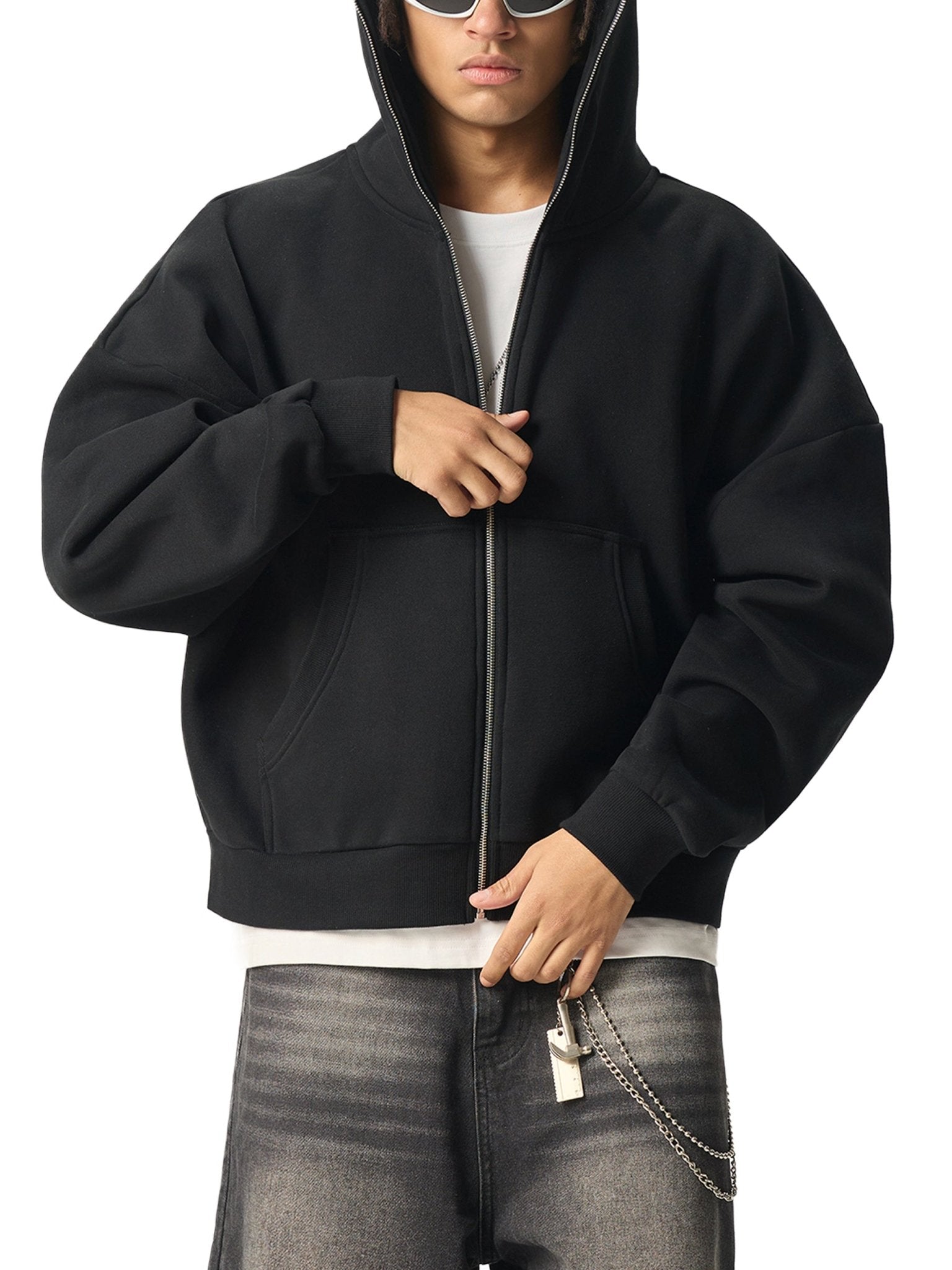 Person wearing a black hoodie with a white shirt and gray jeans on a white background