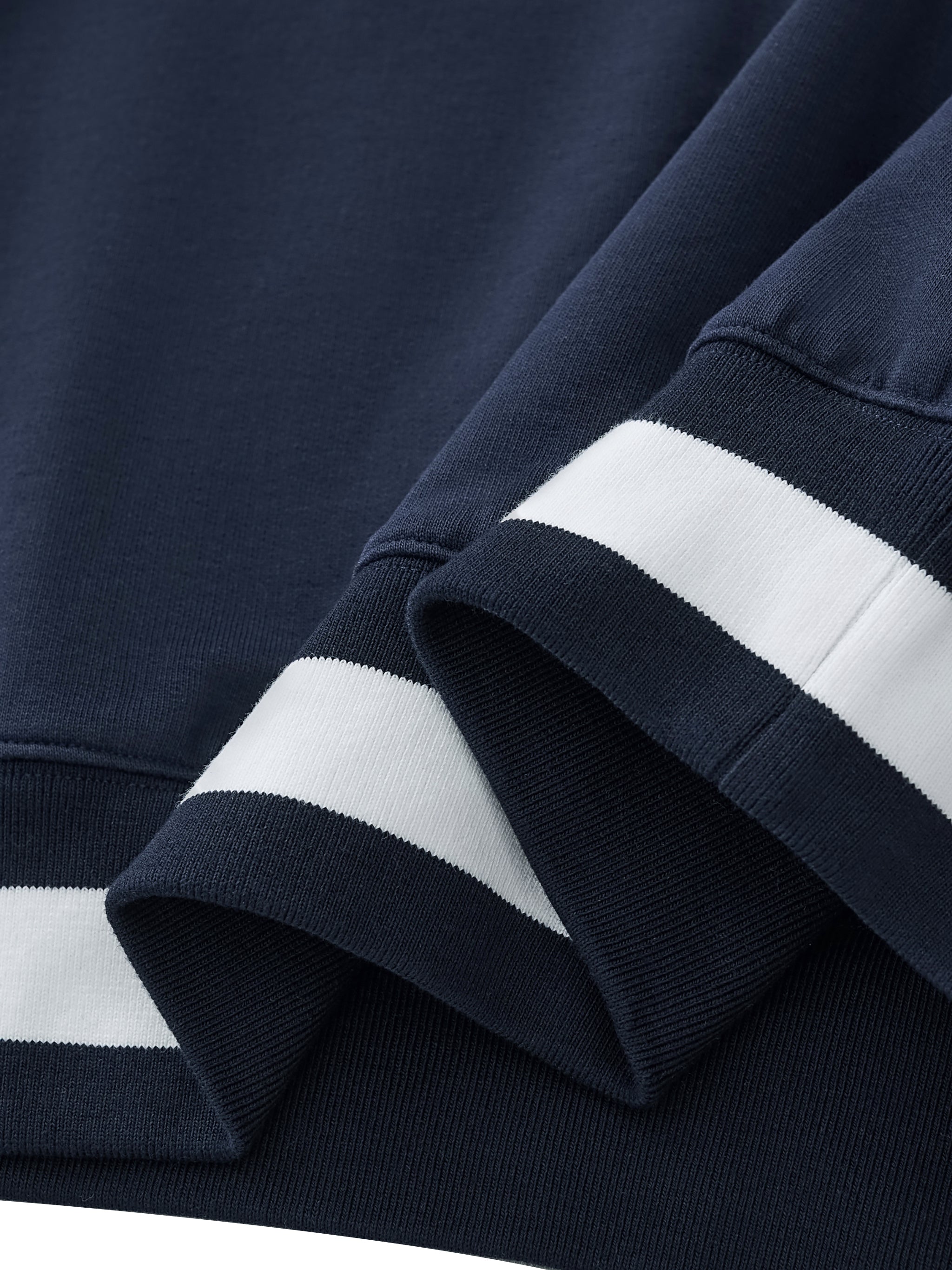 Close-up of navy blue sweatshirt with white stripes on cuffs and hem
