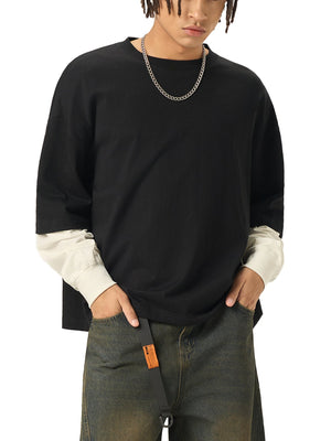 Person wearing a black oversized sweater with white cuffs and hem, paired with dark jeans on a white background.