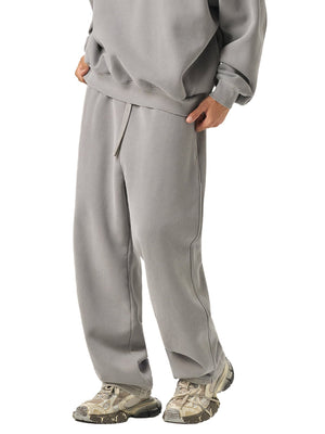 Person wearing a gray tracksuit with beige shoes on a white background