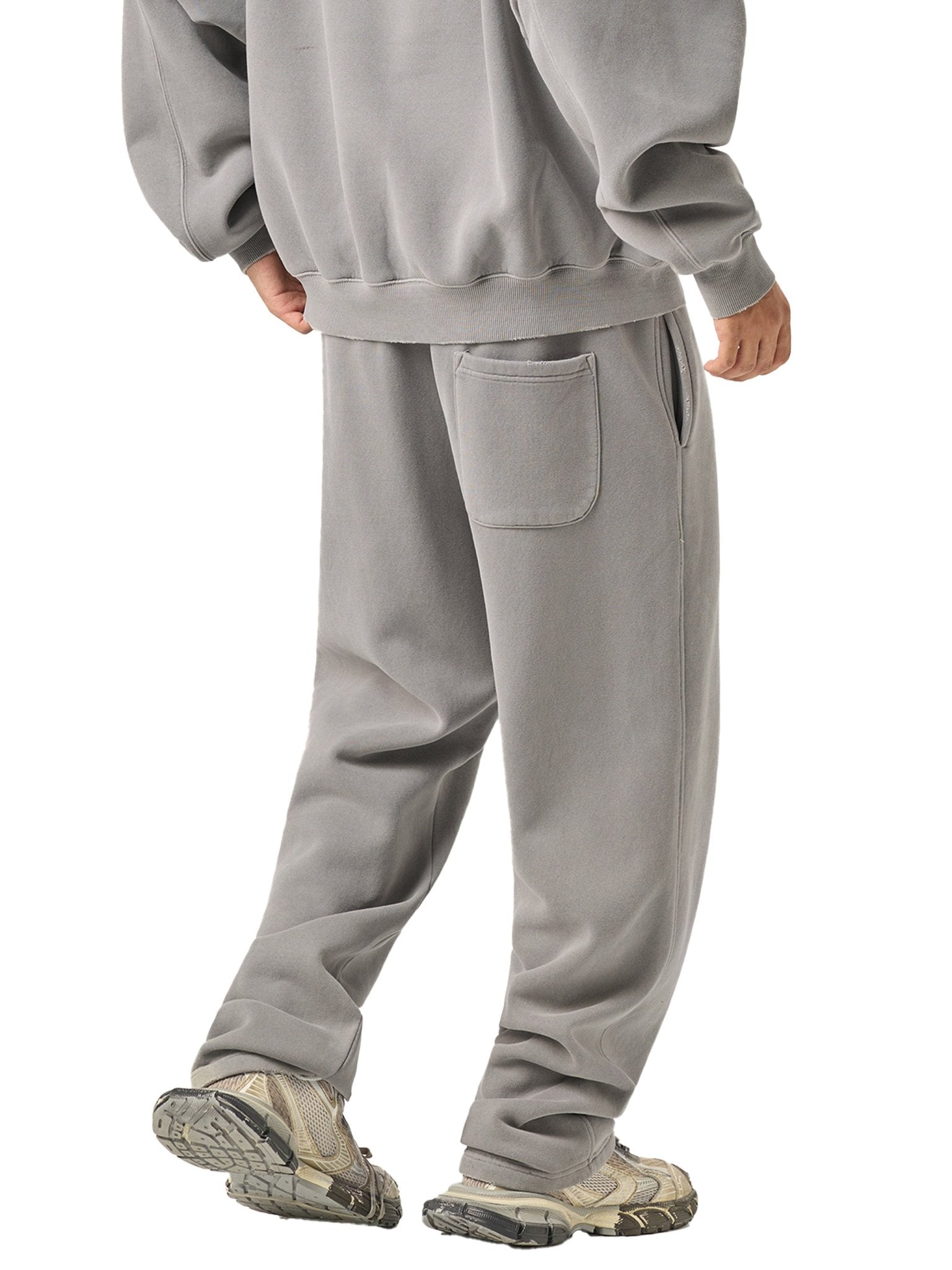 Person wearing a gray tracksuit on a white background