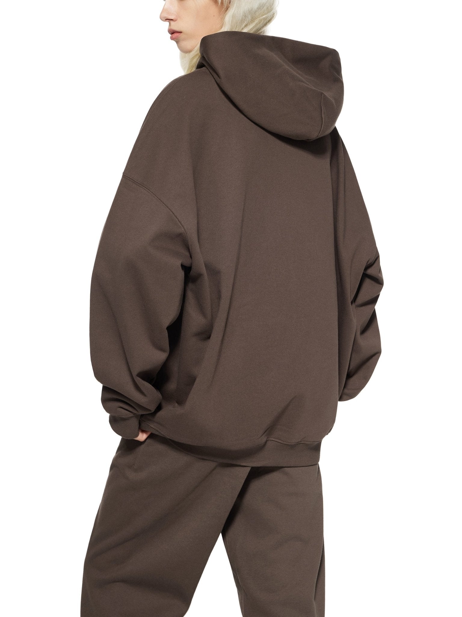 Person wearing a brown hoodie and pants on a white background