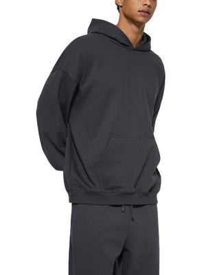 Person wearing a black hoodie and pants on a white background