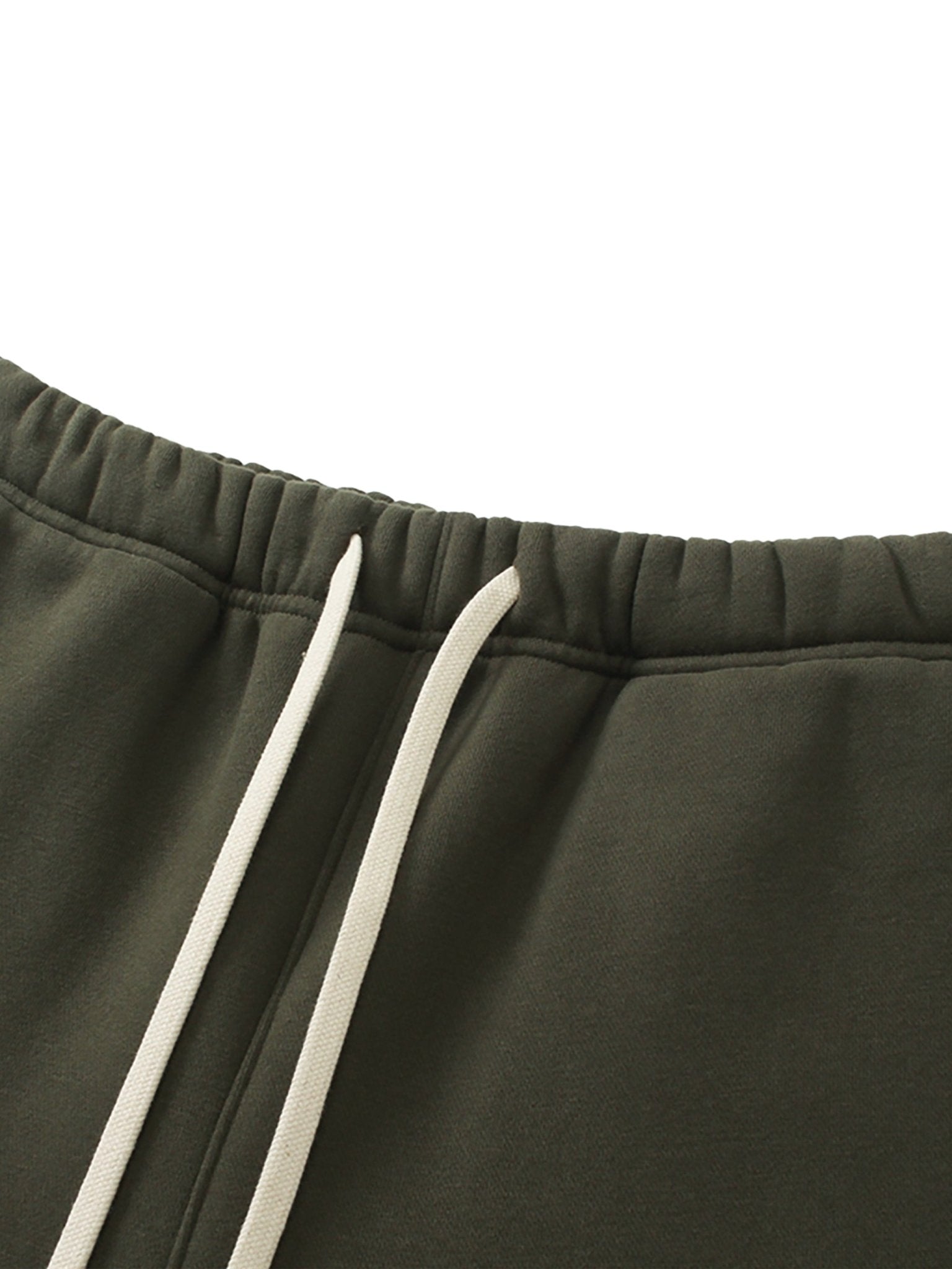 Close-up of dark green sweatpants with white drawstring on a white background