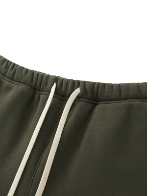 Close-up of dark green sweatpants with white drawstring on a white background