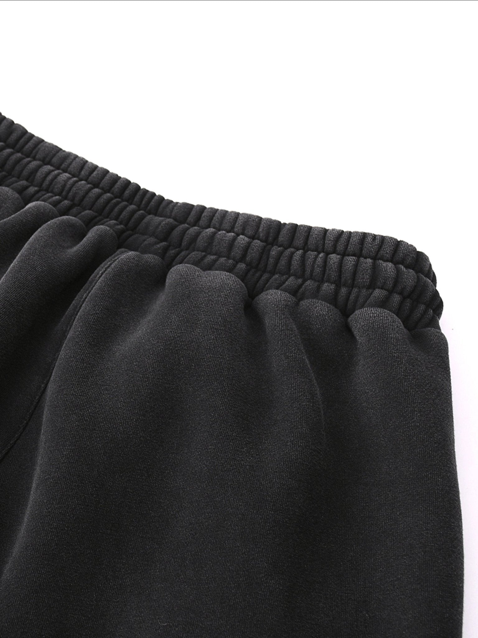Close-up of black sweatpants with a white background