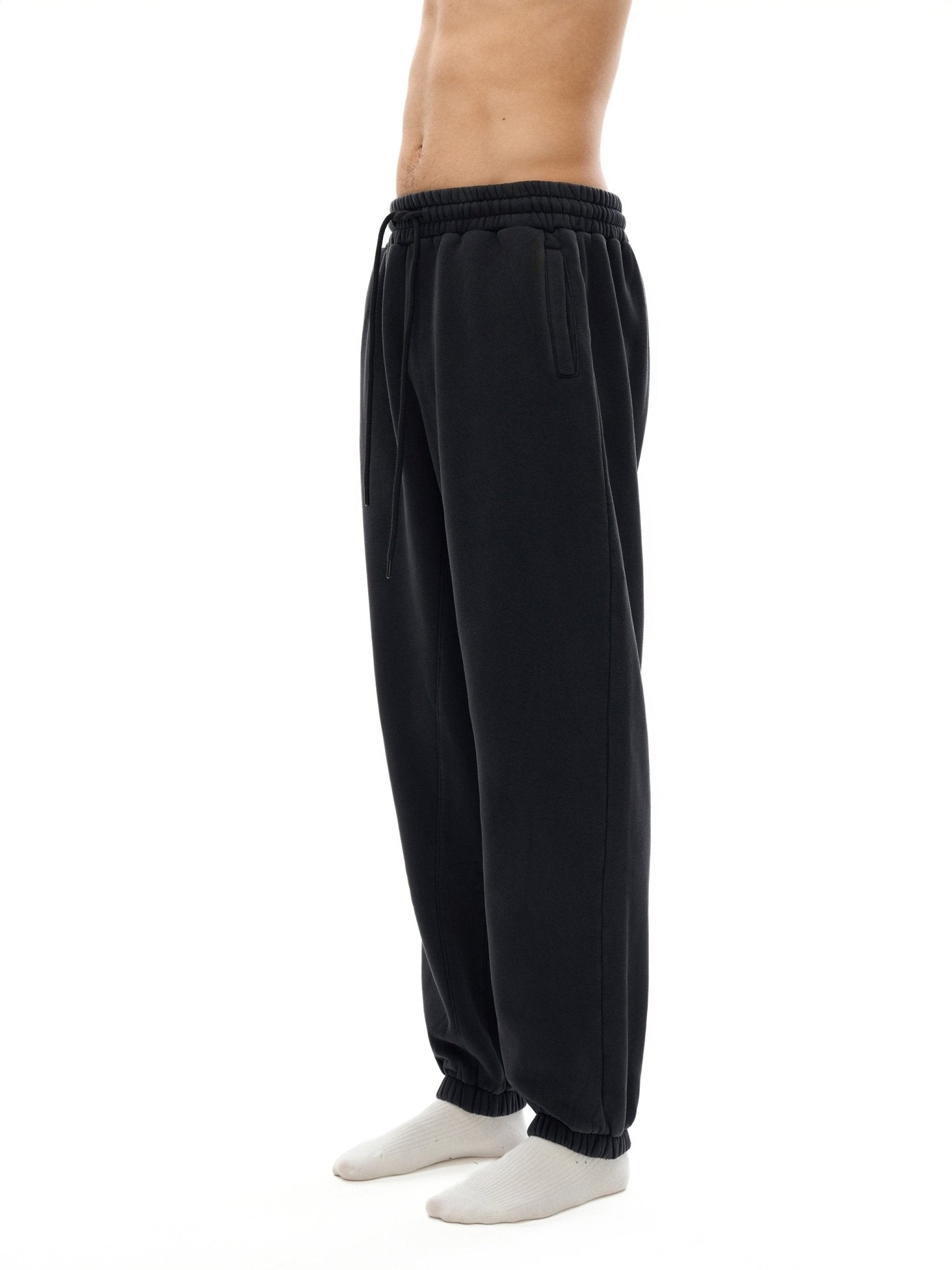 Black sweatpants worn by a person on a white background