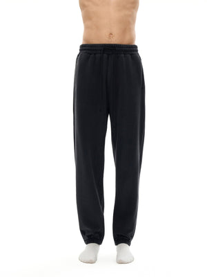 Black sweatpants worn by a person on a white background