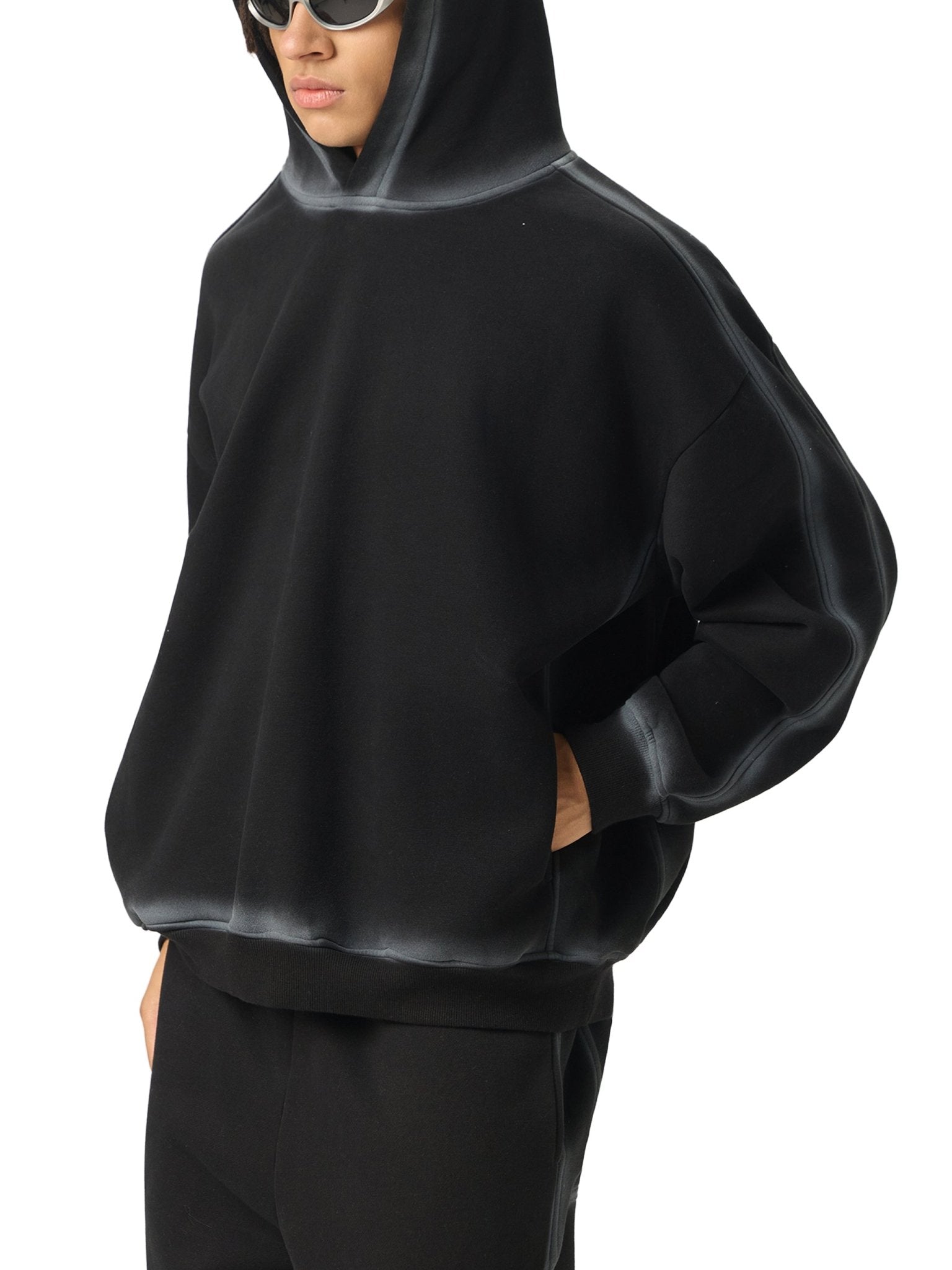 Person wearing a black hoodie and pants on a white background