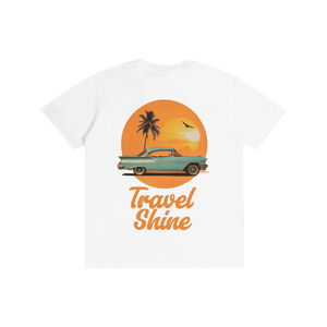 A white short-sleeve t-shirt with a retro graphic on the front. The graphic features a teal vintage car parked in front of a large orange sun with a palm tree silhouette, above the text 'Travel Shine' in orange script.