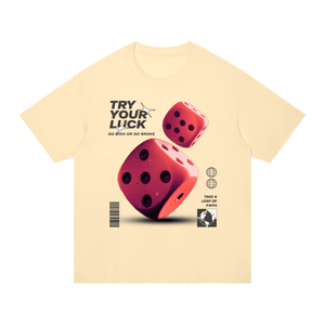 A pale cream-colored short-sleeve t-shirt with a graphic print featuring two red dice, the text 'TRY YOUR LUCK' and 'GO BICH OR GO BROKE', and small black-and-white icons on a plain white background.