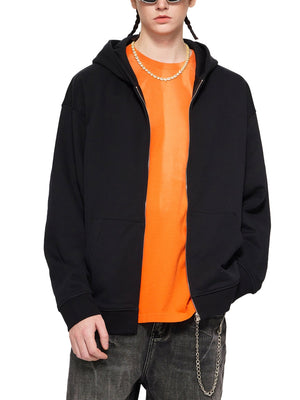 Person wearing a black hoodie over an orange shirt on a white background